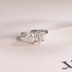 a three stone diamond ring sitting on top of a piece of paper