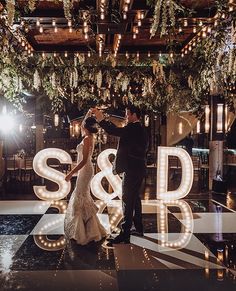 a bride and groom dancing on the dance floor at their wedding reception in front of large letters that spell out s & b