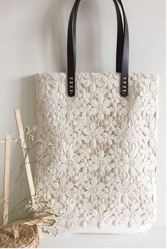 a white tote bag sitting on top of a table next to a vase with flowers