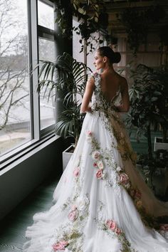 a woman in a wedding dress looking out the window