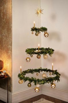 a christmas tree with ornaments hanging from it's sides and candles in the middle