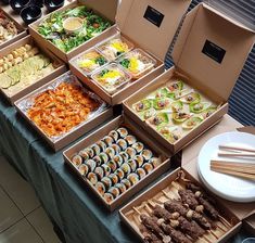 a table topped with lots of boxes filled with food and plates on top of it