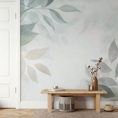 a wooden bench sitting in front of a wall with leaves painted on it and a vase filled with flowers