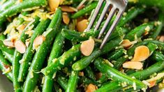 a close up of a plate of food with green beans and almonds