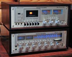 two stereo equipment sitting on top of a wooden table