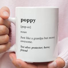 a person holding a coffee mug with the words poppy written on it in different languages