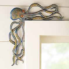 an octopus is hanging on the wall next to a white frame with a mirror in it