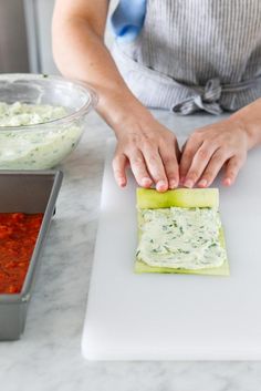 a woman in an apron preparing food on a cutting board with dips and sauce