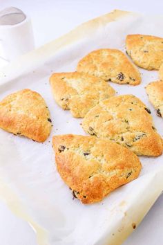 nine biscuits on a baking sheet with a roll in the middle and two cups next to them