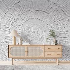 a white and wood sideboard in front of a wall with an intricate design on it