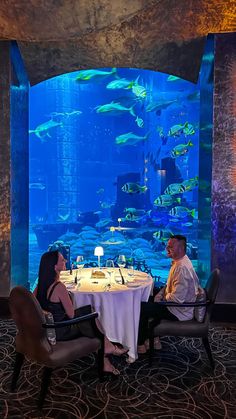 two people sitting at a table in front of an aquarium