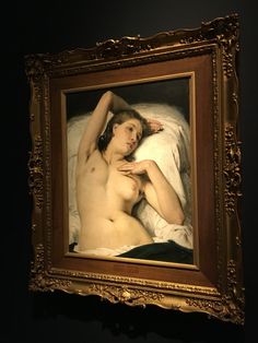 a nude woman laying on top of a bed under a blanket in a gold frame