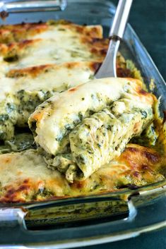 a casserole dish with spinach and cheese being scooped from the casserole