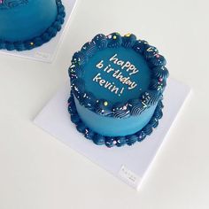 two blue birthday cakes sitting on top of each other in front of a white table