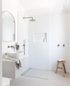 a white bathroom with a walk in shower next to a toilet and sink under a mirror