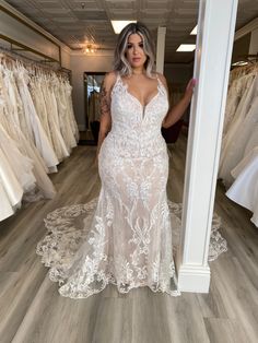 a woman standing in front of a rack of wedding dresses