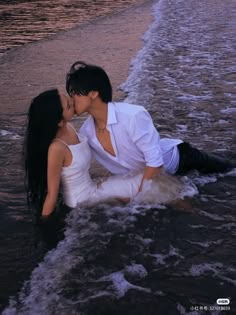 a man and woman kissing in the ocean