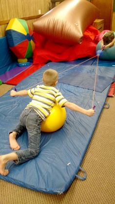 a young boy is playing on an inflatable ball