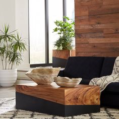 a living room with a black couch and wooden table in front of a large window