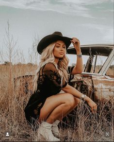 Girl in field, blonde western vibe with black felt cowboy hat and western silver jewelry in black western lace dress and tan cowgirl boots, posed crouched down Western Female Photoshoot, Cowboy Hat Pictures Photo Shoot, Vintage 50s Photoshoot, Cowgirl Inspired Photoshoot, Western Whiskey Photoshoot, Southern Photoshoot Ideas, Cowgirl Themed Photoshoot, Western Outdoor Photoshoot