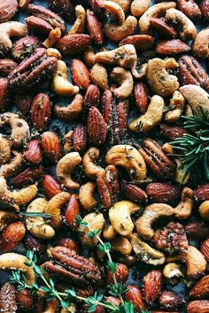 nuts and rosemary sprigs are mixed together on a baking sheet to make a nutritious snack