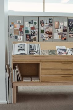 a wooden desk with many pictures on the wall behind it and bookshelf below