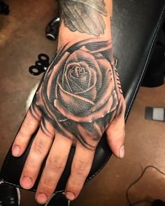 a hand with a black rose tattoo on it's left arm and the middle finger