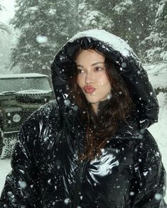 a woman standing in the snow wearing a black jacket