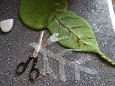 scissors are laying on the ground next to a leaf