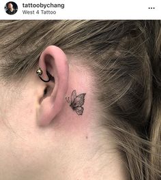 a woman's ear with a small butterfly tattoo on her left behind the ear