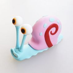 a close up of a toy snail on a white surface with blue and pink colors