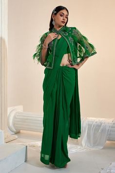 Green solid pre-draped saree with in net georgette base. Paired with a padded sleeveless blouse and feather detailed cape.
Components: 3
Pattern: Embroidered
Type Of Work: Sequin, Cutdana
Neckline: Mandarin
Sleeve Type: Three-quarter Flared
Fabric: Net Georgette, Crepe
Color: Green
Other Details: 
Attached lining
Length: 
Saree Skirt: 41 inches
Blouse: 13 inches
Cape: 17.5 inches
Occasion: Mehendi and Haldi - Aza Fashions Formal Fitted Green Saree, Green Formal Pre-draped Saree, Green Draped Party Sets, Green Blouse Piece For Evening With Traditional Drape, Green Cutdana Pre-draped Saree For Evening, Green Evening Dupatta, Saree Skirt, Feather Cape, Cape Set