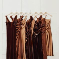 four dresses hanging on a rack in front of a white wall