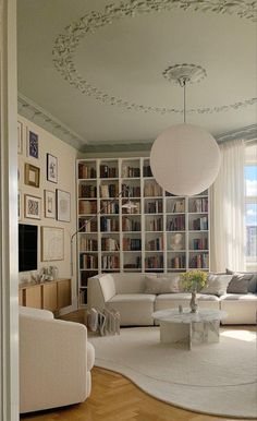 a living room filled with lots of furniture and bookshelves on the wall next to a window