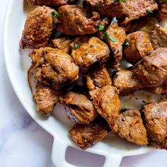 a white plate topped with meat covered in parsley