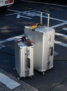 two silver suitcases sitting on top of a parking lot next to a white van