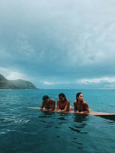 three people are sitting on surfboards in the water