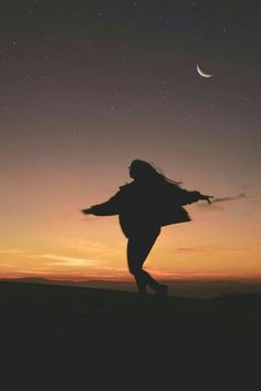 a woman is silhouetted against the night sky with her arms spread out in the air