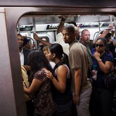 a group of people standing on a subway train with their arms around each other as they look out the window