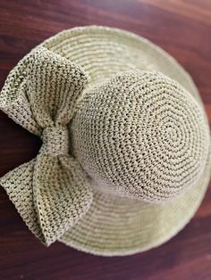 a close up of a hat on a wooden surface with a bow at the top