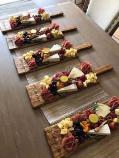 four wooden planks with different types of cheese and fruit arranged on top of each other