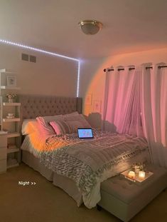 a bedroom with a laptop on the bed and pink drapes hanging from the ceiling