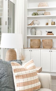 a living room filled with lots of white furniture and shelves covered in wicker baskets