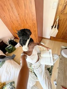 a woman sitting on top of a bed next to a hair dryer and book