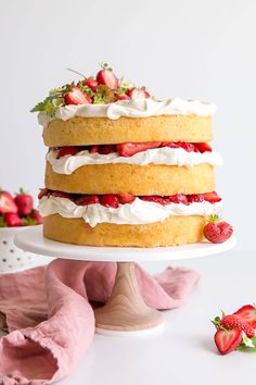 a three layer cake with strawberries on top and whipped cream frosting around the edges