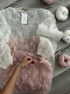 a woman is cutting fabric with scissors on the floor next to yarn balls and needles