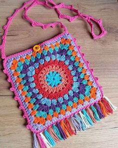 a colorful crocheted bag sitting on top of a wooden table next to a string