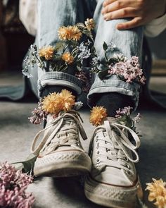 someone is sitting on the floor with flowers in their shoes