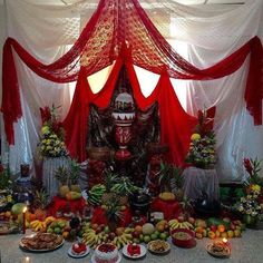 a table topped with lots of fruits and vegetables next to a white curtain covered wall