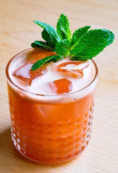 an orange drink with ice and mint garnish